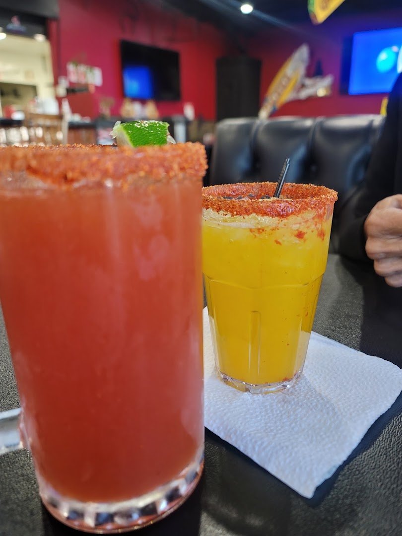 Margaritas beside small plates in an art-filled space.